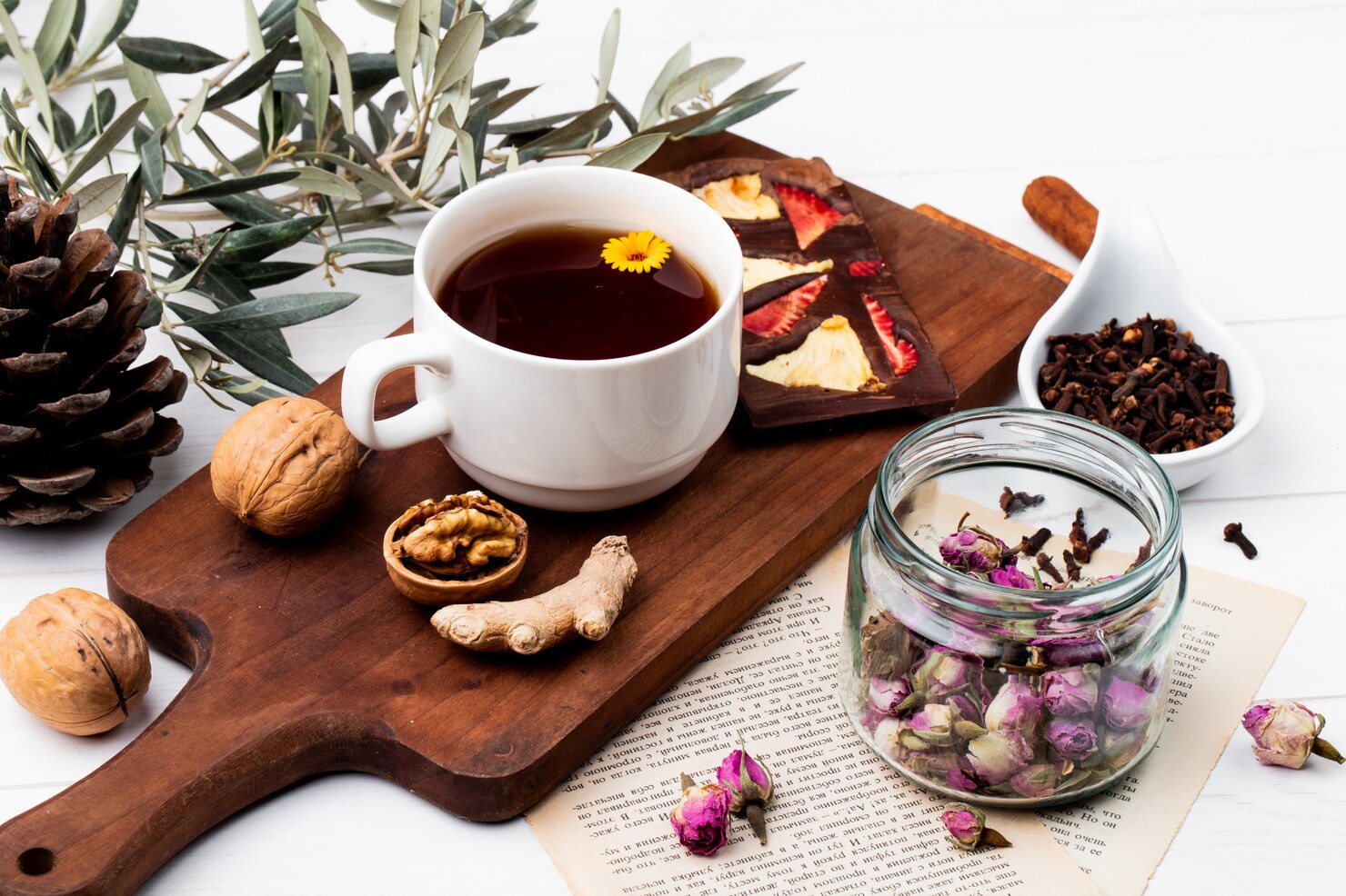 Warm herbal tea in a ceramic cup surrounded by dried botanical ingredients on a wooden table